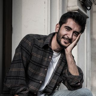 A man in his thirties sitting outside a house.