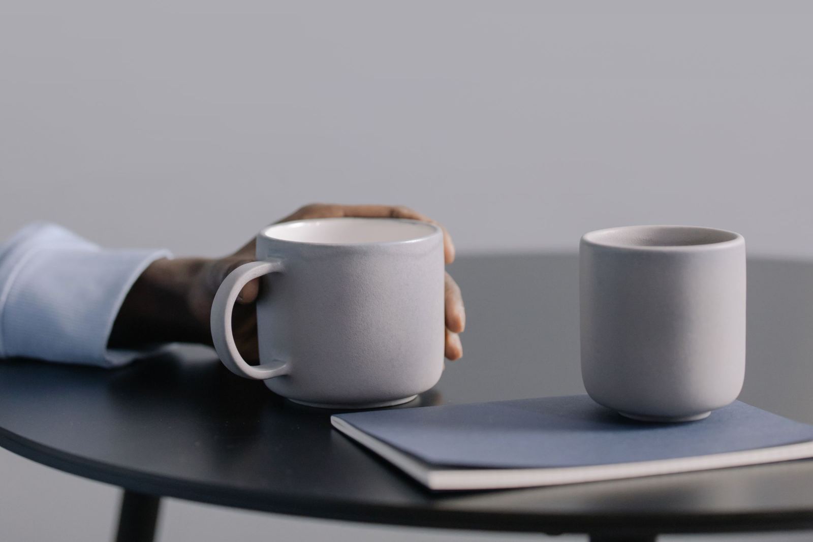 A kitchen table set for a conversation: two cups and a notepad in natural light.